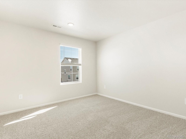 empty room with carpet floors, visible vents, and baseboards