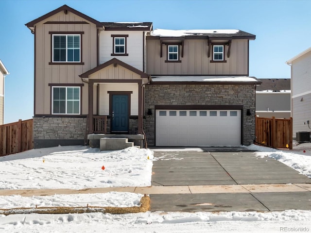 view of front of home with driveway, stone siding, an attached garage, fence, and board and batten siding