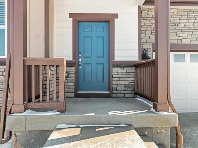 property entrance with a garage and stone siding