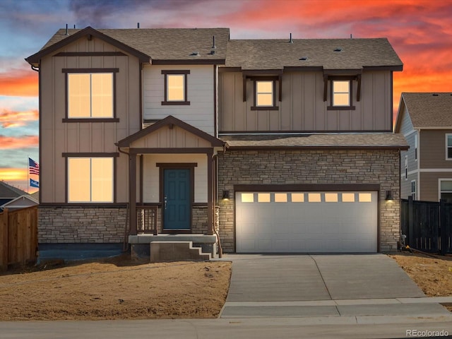 view of front facade featuring fence, an attached garage, concrete driveway, stone siding, and board and batten siding