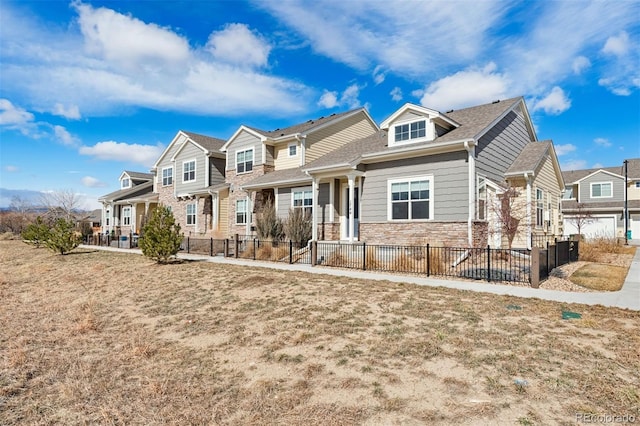 view of front of property with stone siding, a fenced front yard, and a residential view