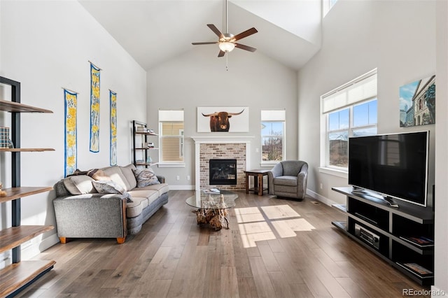 living room featuring ceiling fan, a fireplace, high vaulted ceiling, and wood finished floors