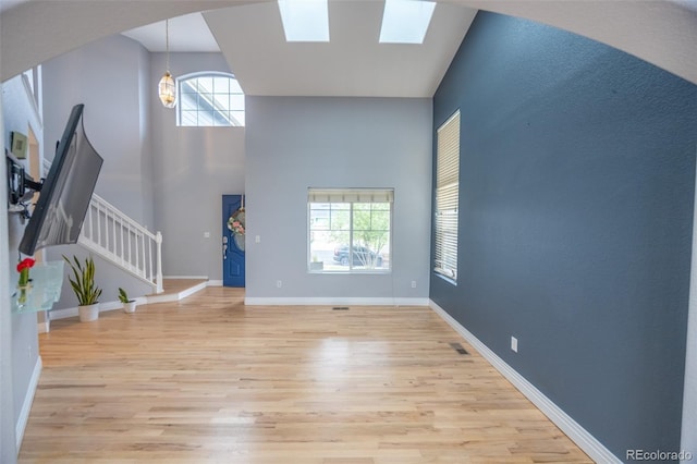 foyer entrance with stairway, baseboards, a healthy amount of sunlight, and light wood-style floors