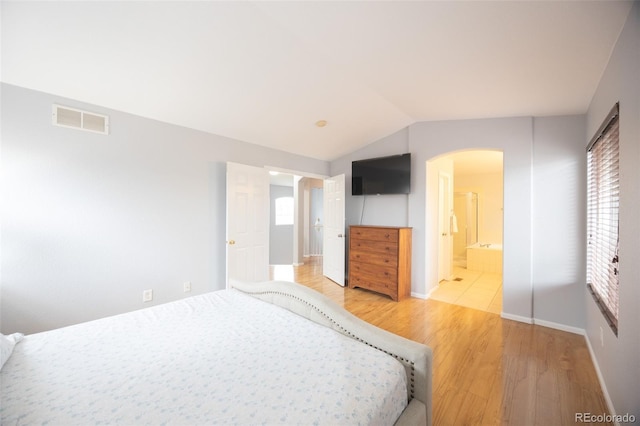 unfurnished bedroom with arched walkways, light wood-type flooring, baseboards, visible vents, and lofted ceiling