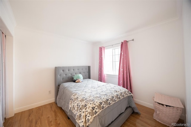 bedroom with baseboards, ornamental molding, and light wood-type flooring
