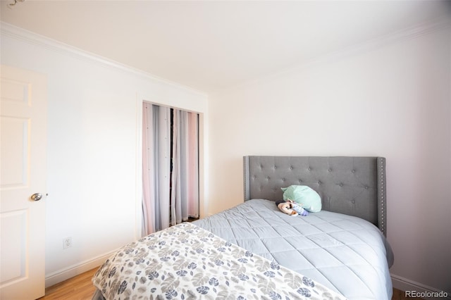 bedroom featuring baseboards, ornamental molding, and light wood-type flooring