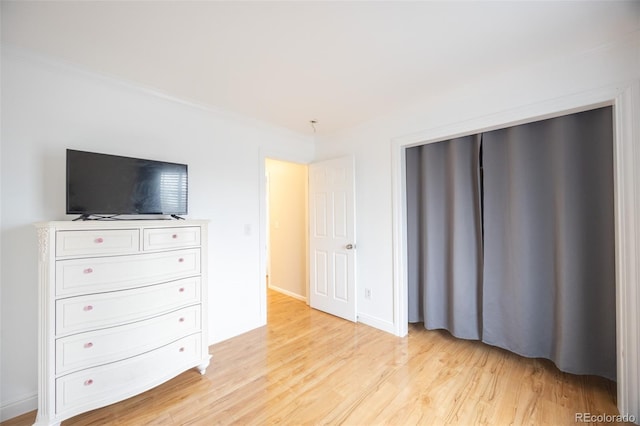 bedroom featuring crown molding and light wood finished floors