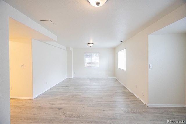 unfurnished room with baseboards and light wood-style floors