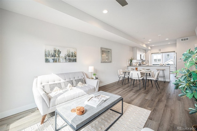 living room with visible vents, baseboards, and wood finished floors