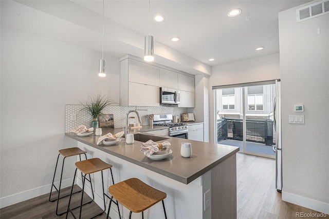 kitchen with tasteful backsplash, visible vents, appliances with stainless steel finishes, a sink, and wood finished floors