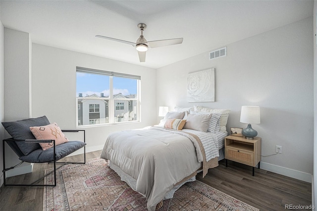 bedroom with ceiling fan, wood finished floors, visible vents, and baseboards