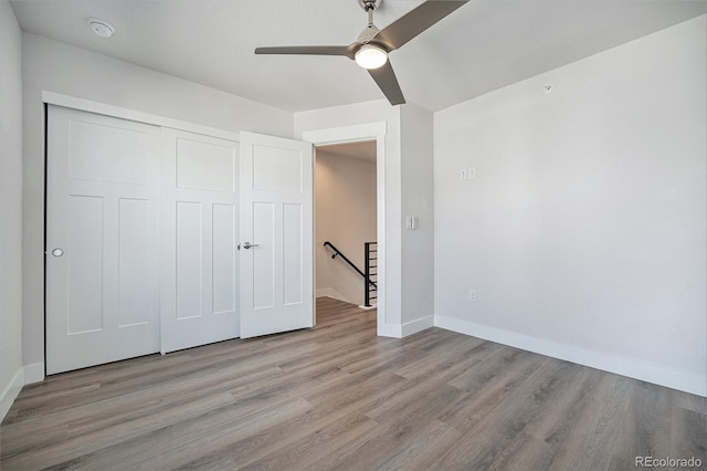 unfurnished bedroom with ceiling fan, a closet, baseboards, and wood finished floors