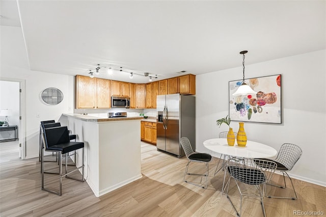 8200 E 8th Ave Unit 5-204, Denver, CO 80230 - kitchen featuring appliances with stainless steel finishes, a peninsula, light wood finished floors, and light countertops