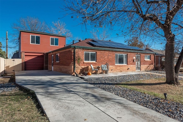 back of house featuring a patio area, a garage, and solar panels