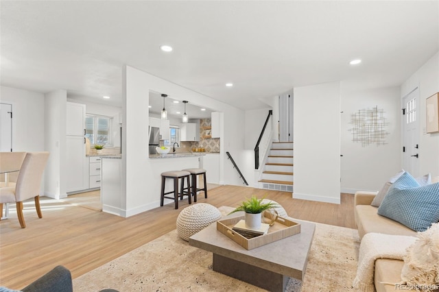 living room featuring sink and light hardwood / wood-style flooring