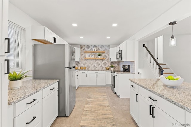 kitchen with pendant lighting, stainless steel appliances, tasteful backsplash, light stone countertops, and white cabinets