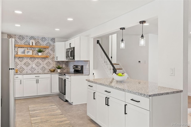 kitchen featuring appliances with stainless steel finishes, decorative light fixtures, white cabinetry, decorative backsplash, and light stone countertops