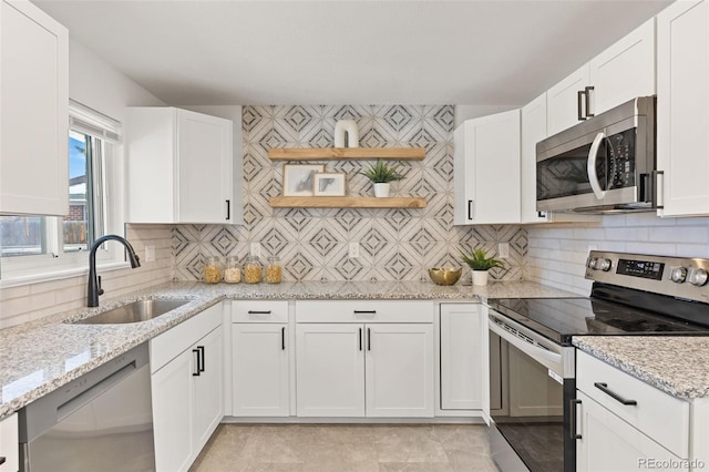 kitchen with white cabinetry, sink, stainless steel appliances, and light stone countertops