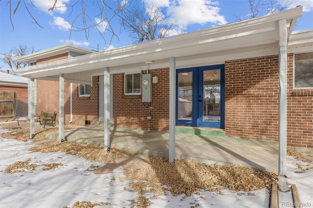 snow covered rear of property with french doors