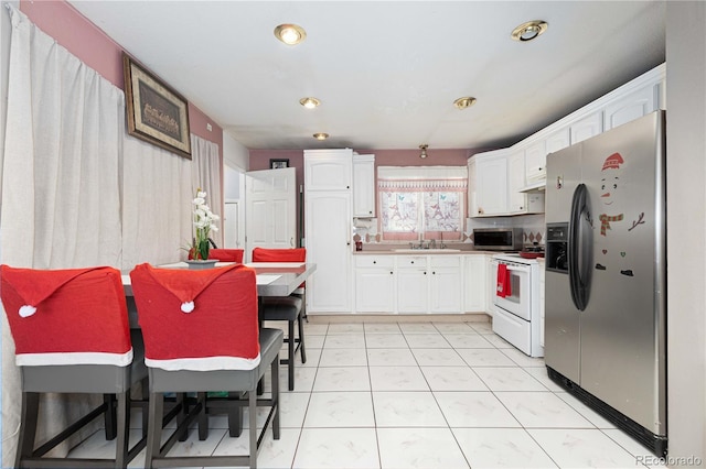 kitchen with appliances with stainless steel finishes, light tile patterned floors, white cabinetry, and sink