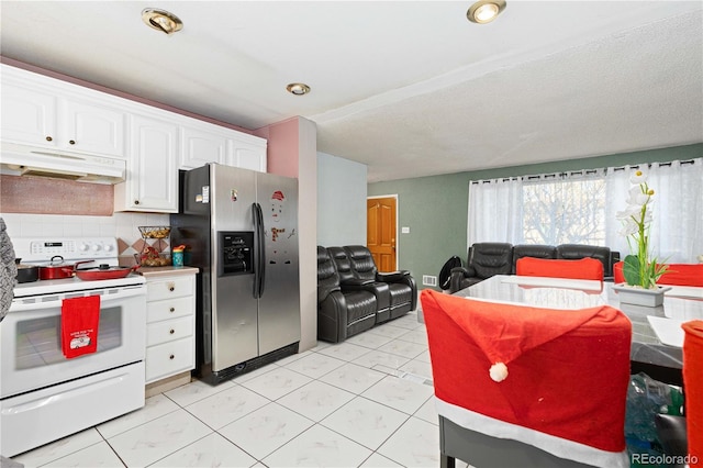 kitchen with stainless steel fridge, tasteful backsplash, light tile patterned floors, electric range, and white cabinetry