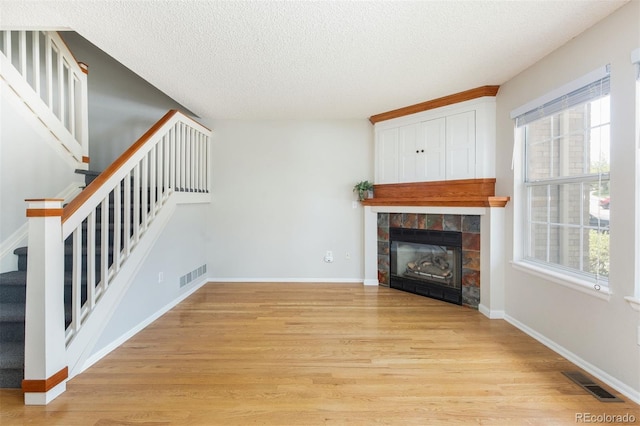 3098 W 107th Pl Unit C, Westminster, CO 80031 - unfurnished living room featuring stairs, a textured ceiling, light wood-type flooring, a fireplace, and baseboards