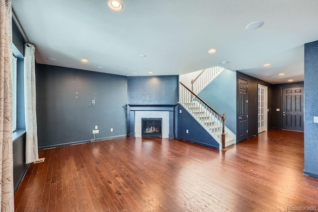 unfurnished living room featuring a tiled fireplace and dark hardwood / wood-style floors