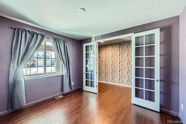 spare room with french doors, dark hardwood / wood-style flooring, and a textured ceiling