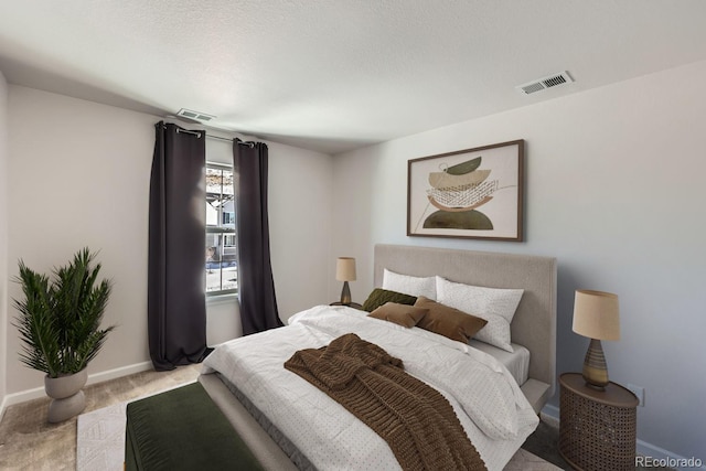 bedroom with light colored carpet and a textured ceiling