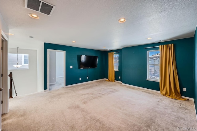 interior space featuring a healthy amount of sunlight, light colored carpet, and a textured ceiling