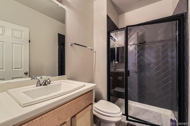 bathroom with vanity, a shower with shower door, and toilet