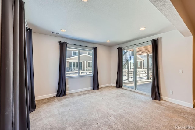 spare room with light colored carpet and a textured ceiling