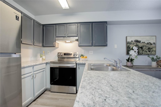 kitchen with gray cabinetry, stainless steel appliances, light wood-type flooring, and sink