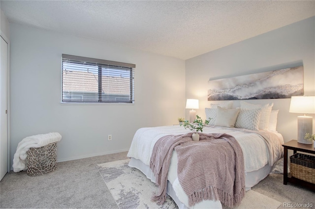 bedroom with light colored carpet and a textured ceiling