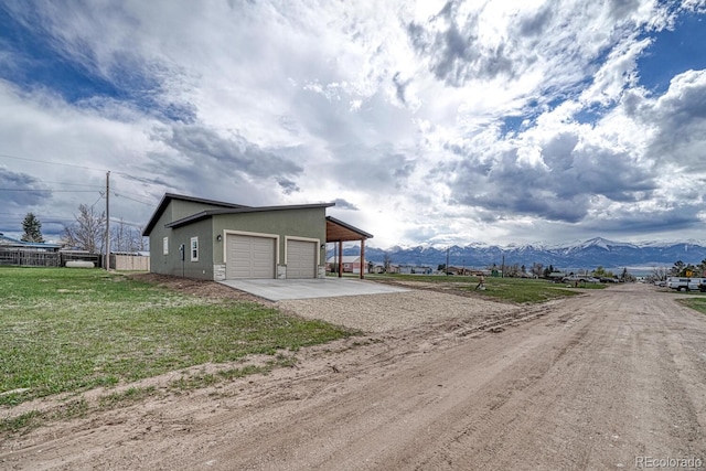 806 S St, Silver Cliff, CO 81252 - view of outdoor structure with dirt driveway, a mountain view, a carport, and an attached garage