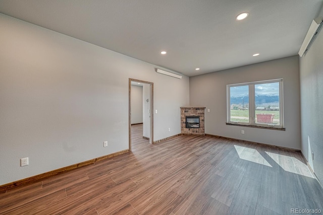 806 S St, Silver Cliff, CO 81252 - unfurnished living room with wood finished floors, recessed lighting, baseboards, a glass covered fireplace, and a wall mounted AC