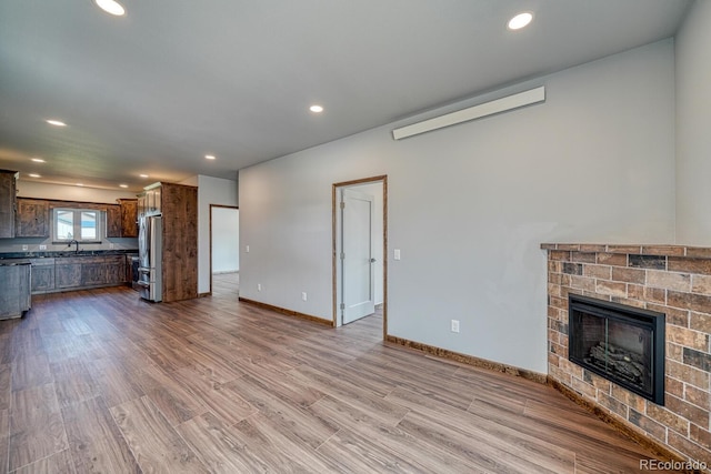 806 S St, Silver Cliff, CO 81252 - unfurnished living room with wood finished floors, recessed lighting, a brick fireplace, baseboards, and a sink