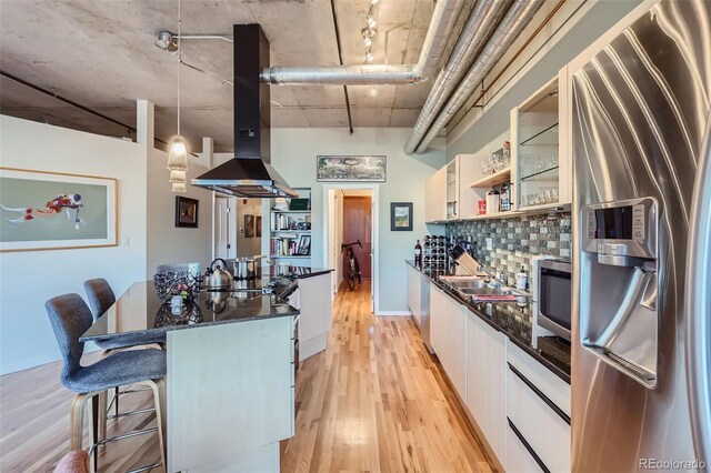 1499 Blake St Unit 5I, Denver, CO 80202 - kitchen featuring appliances with stainless steel finishes, island range hood, light wood finished floors, white cabinetry, and modern cabinets