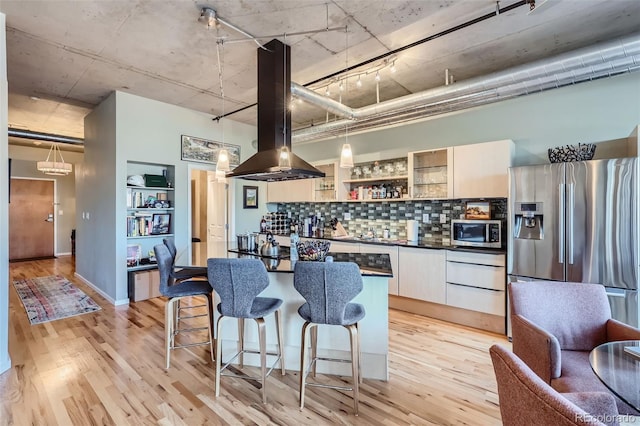 1499 Blake St Unit 5I, Denver, CO 80202 - kitchen with appliances with stainless steel finishes, light wood finished floors, dark countertops, and island range hood