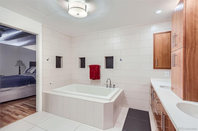 bathroom featuring wood-type flooring, vanity, a bathing tub, and tile walls