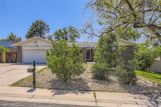 661 S Paris St, Aurora, CO 80012 - view of property hidden behind natural elements featuring driveway, brick siding, and an attached garage