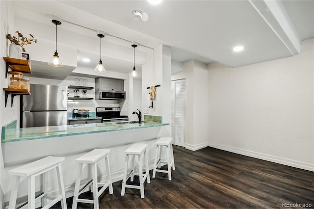 kitchen featuring dark wood-type flooring, stainless steel appliances, a kitchen breakfast bar, hanging light fixtures, and kitchen peninsula