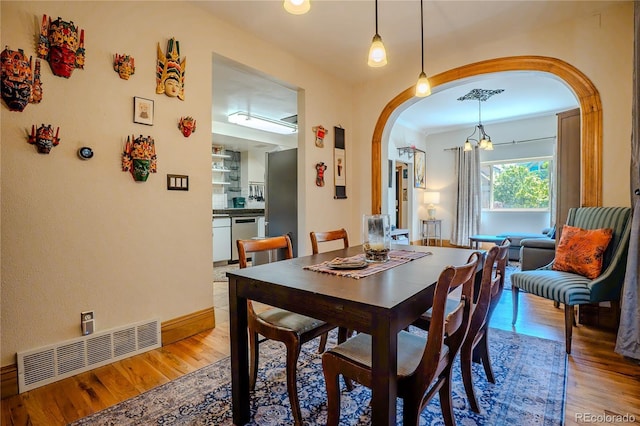433 Fox St, Denver, CO 80204 - dining room featuring arched walkways, light wood-style flooring, baseboards, and a chandelier
