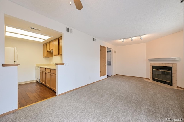 1301 S Cathay Ct Unit 104, Aurora, CO 80017 - unfurnished living room with a tile fireplace, dark carpet, ceiling fan, baseboards, and a sink