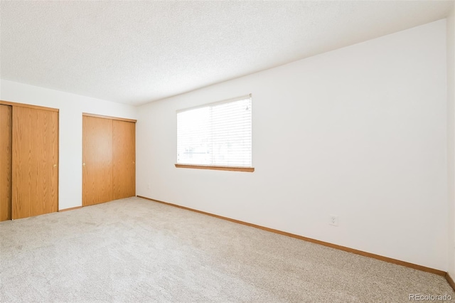 1301 S Cathay Ct Unit 104, Aurora, CO 80017 - unfurnished bedroom featuring two closets, carpet floors, baseboards, and a textured ceiling