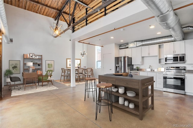 3033 Blake St Unit 121, Denver, CO 80205 - kitchen featuring appliances with stainless steel finishes, finished concrete floors, a towering ceiling, white cabinetry, and recessed lighting