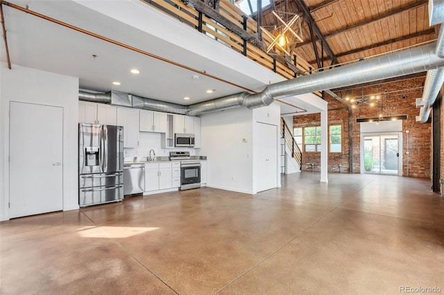 3033 Blake St Unit 121, Denver, CO 80205 - unfurnished living room featuring a high ceiling, brick wall, finished concrete floors, stairs, and recessed lighting