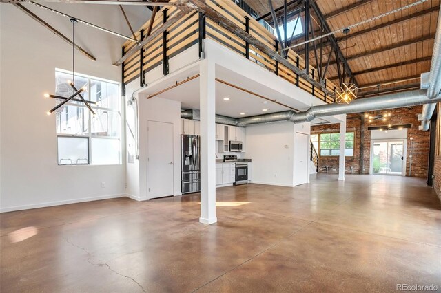 3033 Blake St Unit 121, Denver, CO 80205 - unfurnished living room with a high ceiling, finished concrete flooring, brick wall, and a chandelier