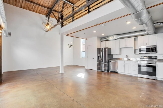 3033 Blake St Unit 121, Denver, CO 80205 - kitchen featuring appliances with stainless steel finishes, concrete flooring, white cabinets, a high ceiling, and recessed lighting