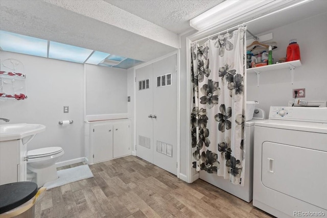 7172 S Vine Cir, Centennial, CO 80122 - bathroom with washer / clothes dryer, wood finished floors, toilet, a textured ceiling, and a shower with shower curtain
